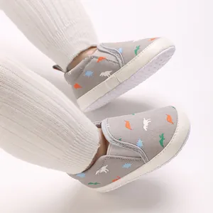 Close-up of baby boy walker shoes with colorful dinosaur patterns and soft white soles