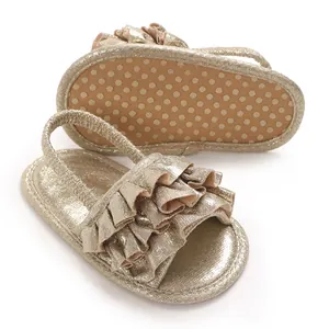 Detail view of golden metallic baby girl sandals with ruffles and elastic strap