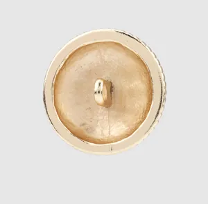 Detail view of the back of a golden metal shank button showing the sewing loop and texture
