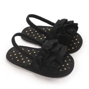 Detailed view of black ruffled baby sandals with golden polka dot pattern on insole