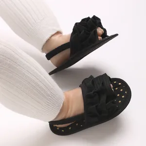Close-up detail of black ruffle baby girl sandals featuring a gold polka dot soft sole design