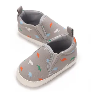 Detail of baby boy walking shoes with colorful dinosaur print on grey canvas