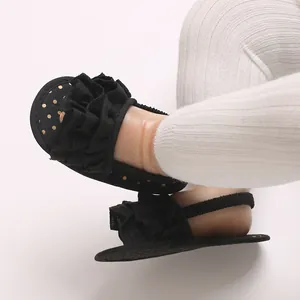 Close-up of black baby sandals with ruffled bands and golden polka dot patterns