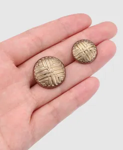 Close-up detail of vintage textured golden metal buttons for luxury fur coats on a hand
