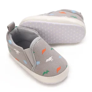 Detail view of baby walking shoes with dinosaur patterns and non-slip dotted soles