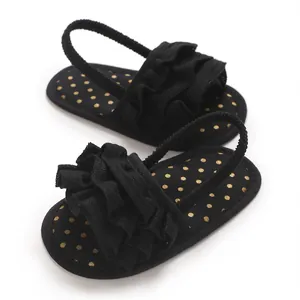 Close-up of black baby girl sandals with ruffles and gold polka dots soft sole