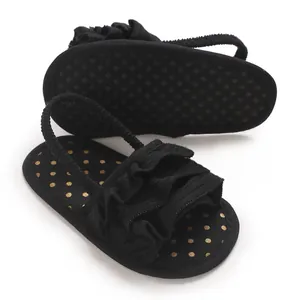 Detailed view of black baby girl sandals with ruffled straps and polka dot insoles