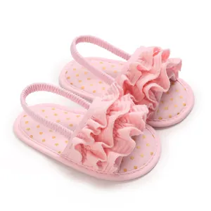 Close-up of pink baby girl ruffle sandals with gold polka dots and soft elastic strap