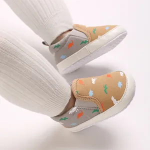 Close-up of baby boy walking shoes with dinosaur pattern and soft anti-slip soles.