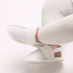 Detailaufnahme weißer Plüsch-Babypuschen für den Winter mit Gummiband und rutschfester Sohle