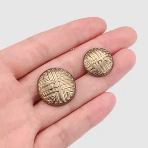 Textured metallic buttons for fur coats and high-end tailoring displayed on a hand