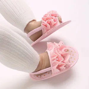 Close-up of pink ruffled baby sandals with elastic back strap and gold dot pattern.