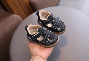 Close-up of retro black baby sandals with white stitching and breathable hollow design