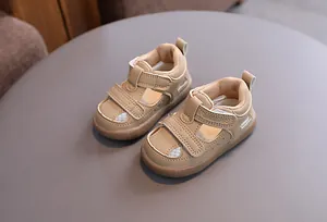 Close-up of beige breathable baby sandals with velcro straps and hollow design