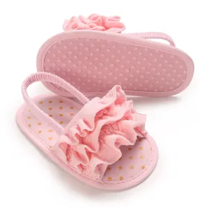 Close-up detail of pink ruffled baby sandals featuring a soft non-slip dot sole and elastic strap.