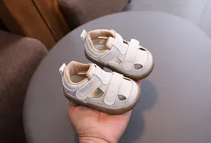 Close-up of white breathable baby sandals with hollow design and velcro straps.