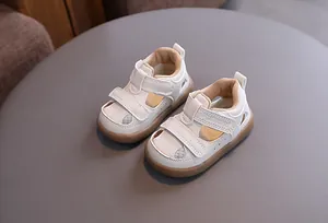 Close-up view of white breathable baby sandals with velcro straps and non-slip brown soles