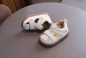 Detailed view of white baby hollow breathable sandals with velcro straps and brown rubber sole