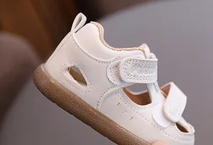 Detailed side view of beige retro baby sandals with breathable hollow cutouts and Velcro