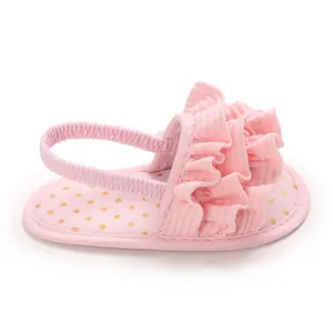 Close-up detail of soft-sole pink baby girl sandals with ruffles and gold polka dots