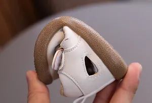 Close-up showing the flexible sole of breathable cream leather hollow baby walking shoes