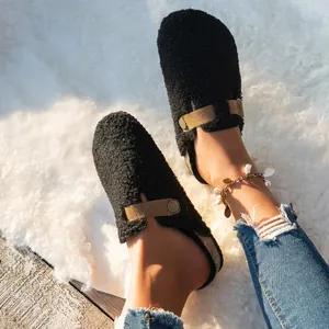 On-foot view of cozy black shearling clogs with buckle strap on a soft fluffy rug