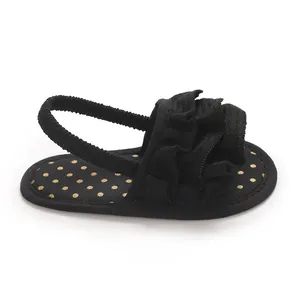 Side view of black infant girl sandal with ruffle detail and gold polka dots