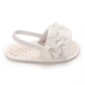 Detailed view of white baby girl sandal featuring elegant ruffles and gold polka dots