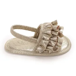 Detail view of golden shimmer baby girl sandals featuring ruffle design and elastic strap.