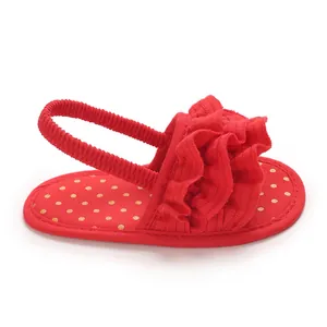 Side profile view of a red ruffled baby girl sandal featuring a golden polka dot insole