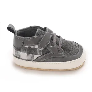 Gros plan de chaussures de marche grises à carreaux pour bébé avec semelles antidérapantes.