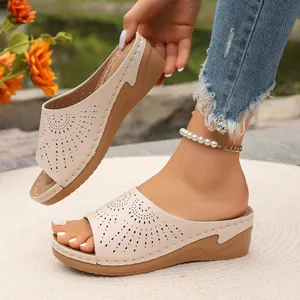 Dettaglio ravvicinato di sandali beige con zeppa da donna e motivi decorativi traforati.