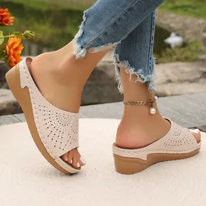 Primo piano di sandali beige con zeppa, motivi traforati laser e cuciture decorative
