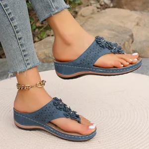 Vue détaillée des tongs à talons compensés bleues avec fleurs 3D et motifs ajourés