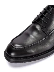 Primer plano detallado de la textura y costuras de zapatos de vestir de cuero negro para hombre