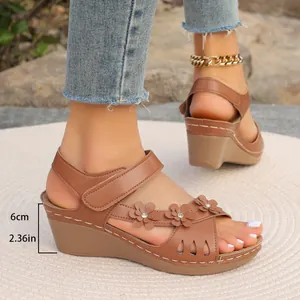 Detailansicht der braunen Keilsandaletten für Damen mit 6 cm Absatz und Blumenakzenten