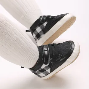 Détail de chaussures de marche pour bébé avec motif à carreaux noir et blanc et semelle souple