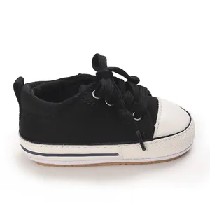 Close-up view of stylish black baby canvas sneakers with white toe caps and soft soles