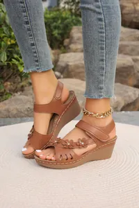 Detailansicht brauner Keilsandalen mit Blumenakzenten und lasergeschnittenem Hohlmuster