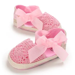 Detailed view of pink crochet lace baby sandals featuring a large decorative ribbon bow