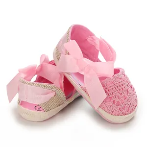 Close-up detail of pink newborn baby girl sandals with elegant lace and ribbon bow