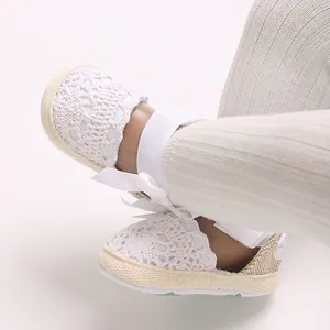 Close-up detail of white lace baby girl sandals with elegant ribbon bow for newborns