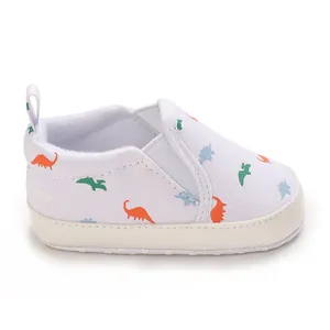 Detailed view of white baby canvas shoe featuring colorful cartoon dinosaur prints.