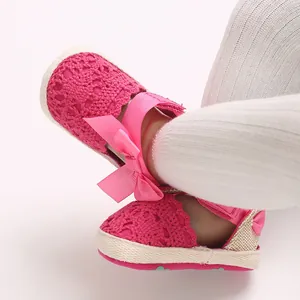 Close-up of pink lace texture and bow detail on newborn girl's summer walking sandals.