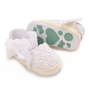 Detailed view of white lace newborn baby girl sandals with ribbon bow and patterned sole