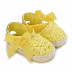 Detailed close-up of yellow newborn baby girl breathable lace sandals with soft ribbon bows