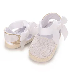 Close-up of white breathable lace baby girl sandals with an elegant bow decoration