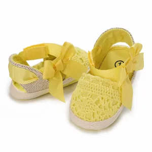 Detailed view of yellow baby lace sandals with decorative ribbon and fabric sole