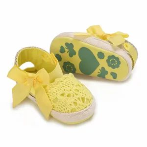 Detail of yellow baby lace sandals showing crochet texture and patterned soft cloth sole.