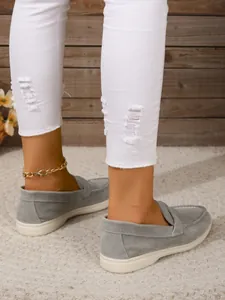 Detailansicht von grauen Slipper aus Wildleder für Damen mit weicher Sohle und Jeans.